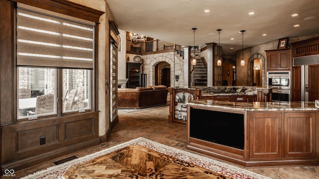 kitchen with decorative light fixtures, double oven, light stone countertops, and a notable chandelier