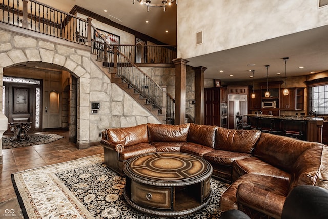 living room with ornate columns, a towering ceiling, and sink