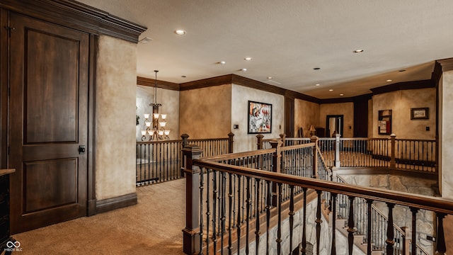 hall with light carpet, an inviting chandelier, and ornamental molding