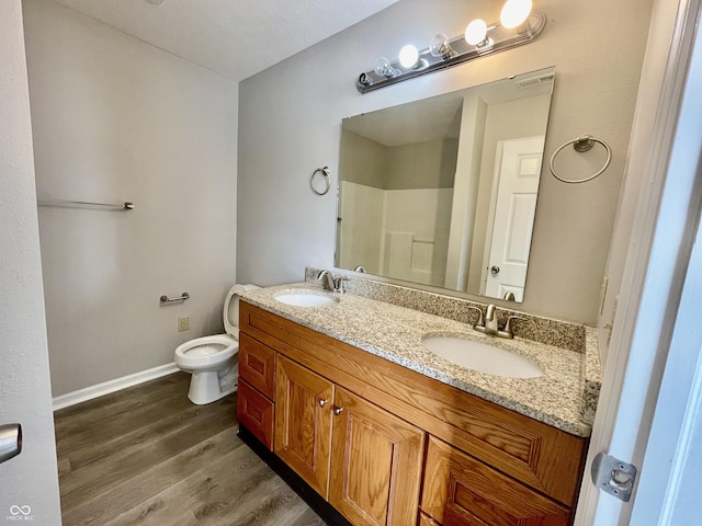 bathroom featuring wood-type flooring, vanity, toilet, and walk in shower