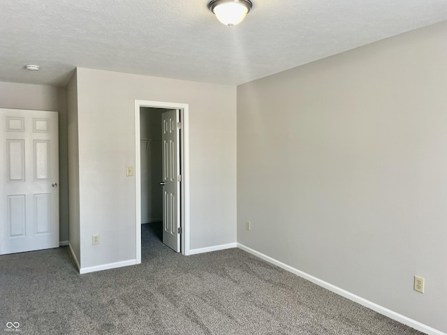 unfurnished bedroom with dark colored carpet, a spacious closet, and a closet