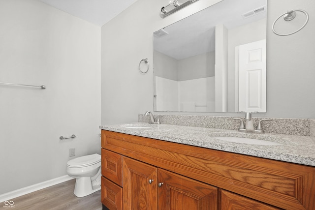 bathroom with toilet, double vanity, a sink, and visible vents