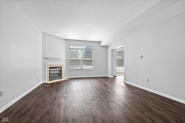 unfurnished living room featuring dark wood-type flooring, a fireplace, a textured ceiling, and baseboards