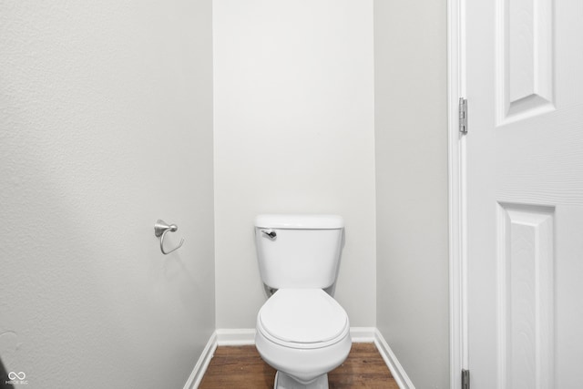 bathroom with toilet, baseboards, and wood finished floors