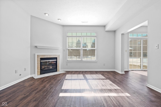 unfurnished living room featuring dark wood-type flooring, a fireplace, and baseboards