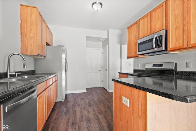 kitchen featuring dark wood finished floors, dark countertops, appliances with stainless steel finishes, a sink, and baseboards