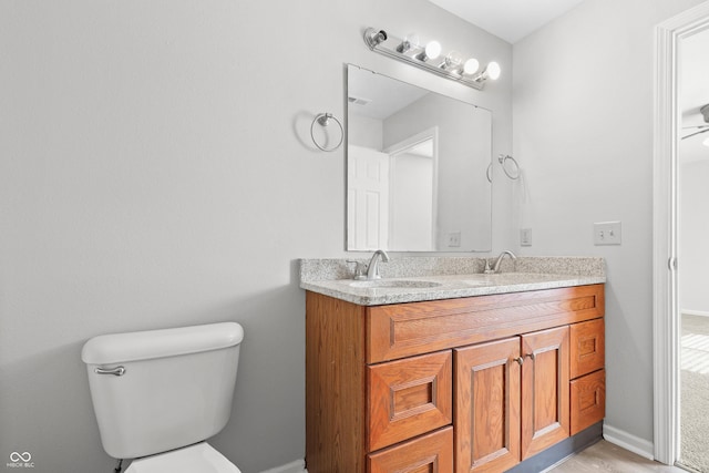 bathroom with double vanity, baseboards, toilet, and a sink