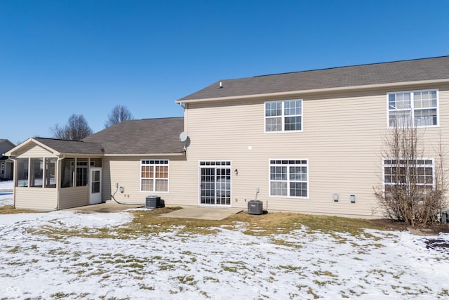 snow covered house featuring a sunroom and central AC