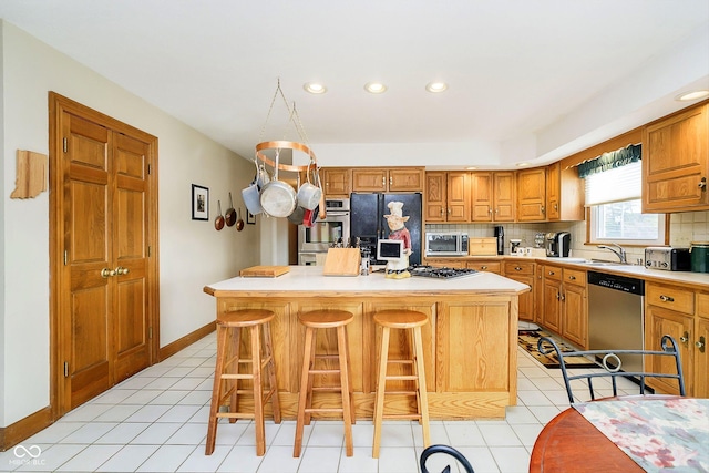 kitchen with appliances with stainless steel finishes, a breakfast bar, a kitchen island, and backsplash