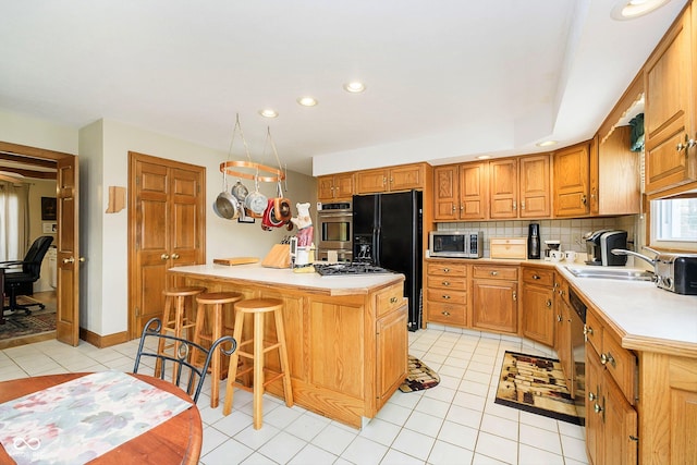 kitchen with sink, a kitchen island, stainless steel appliances, a kitchen bar, and decorative backsplash