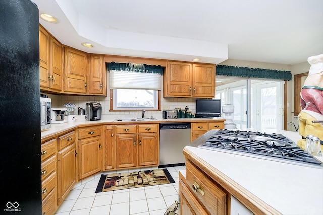 kitchen featuring appliances with stainless steel finishes, sink, light tile patterned floors, and backsplash