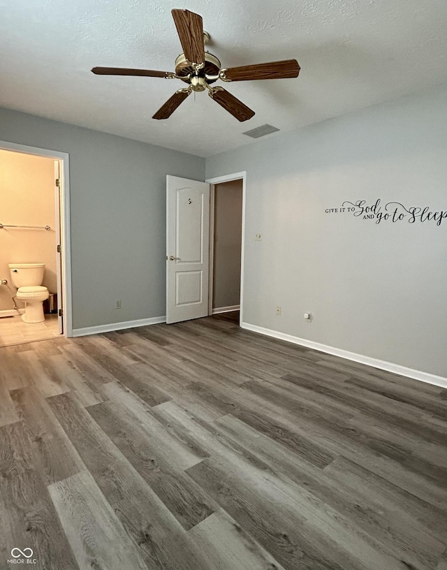 unfurnished bedroom featuring hardwood / wood-style floors, connected bathroom, and ceiling fan