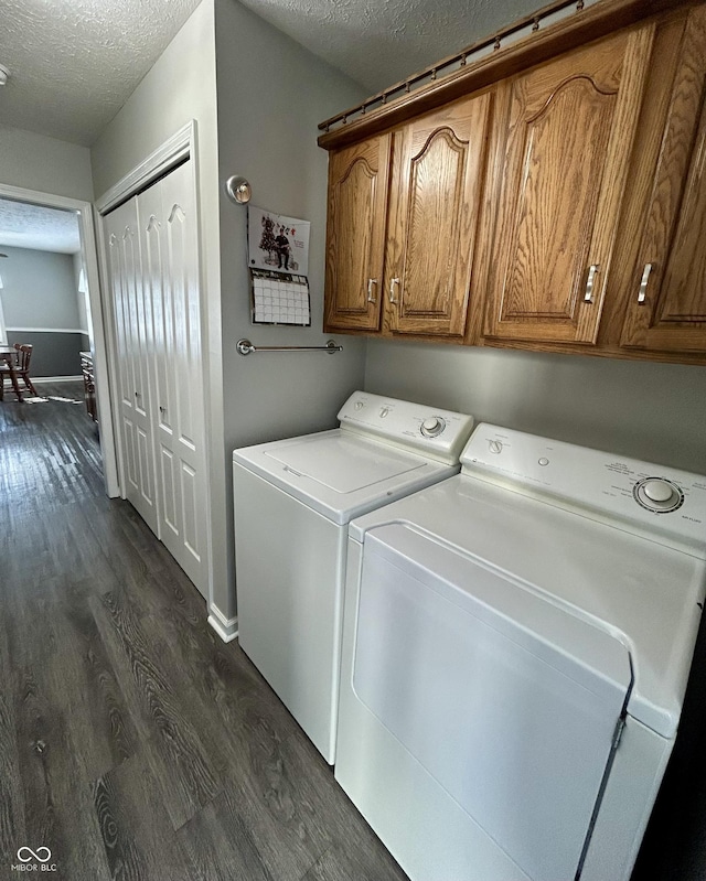 washroom featuring cabinets, a textured ceiling, washer and clothes dryer, and dark wood-type flooring