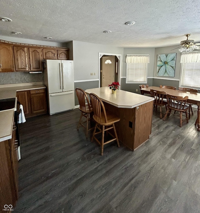 kitchen featuring a center island, ceiling fan, white fridge, dark hardwood / wood-style flooring, and range