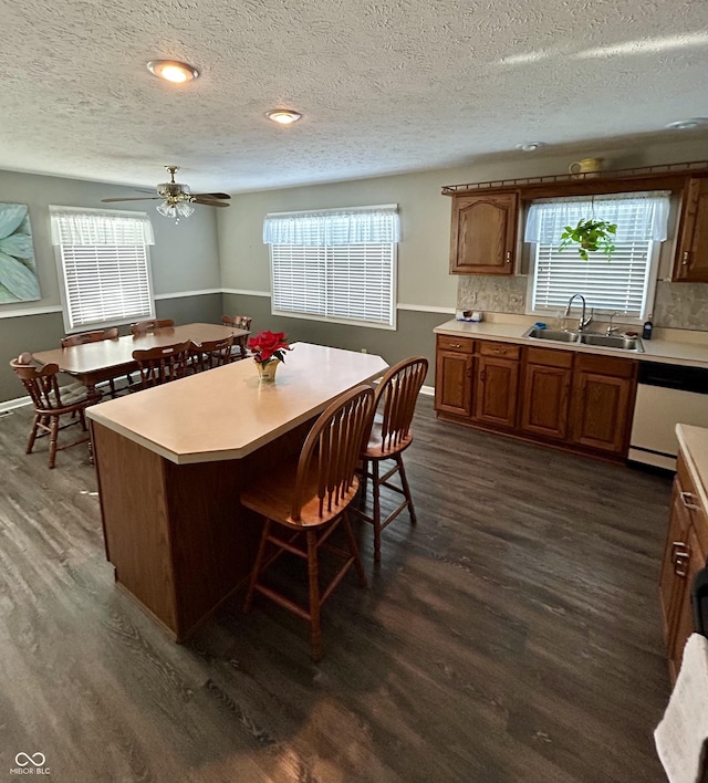 kitchen featuring sink, dark hardwood / wood-style floors, white dishwasher, decorative backsplash, and a kitchen island