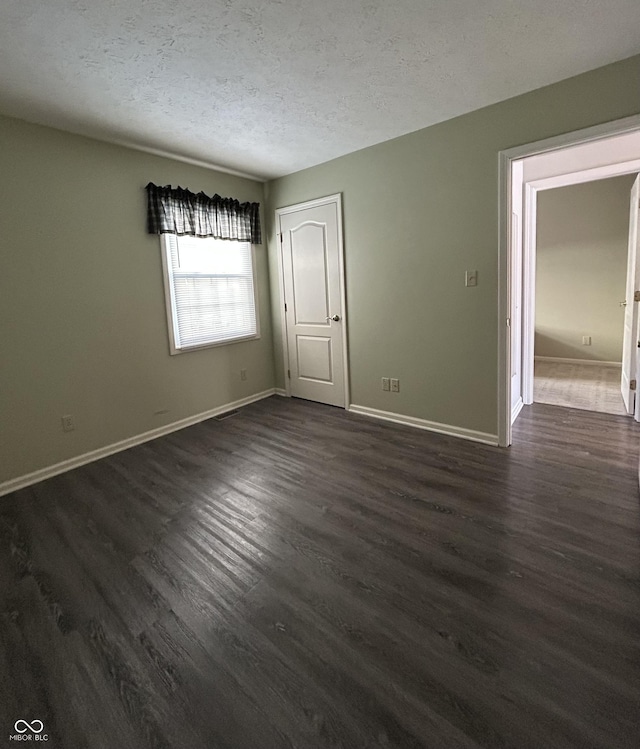 empty room featuring dark hardwood / wood-style floors and a textured ceiling