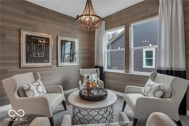 sitting room featuring a chandelier and wooden walls