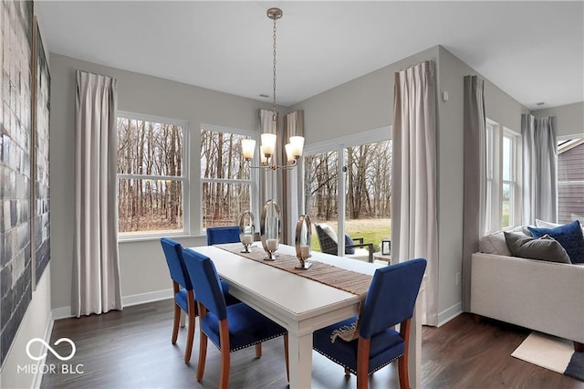 dining area with a healthy amount of sunlight, dark wood-style floors, baseboards, and a notable chandelier