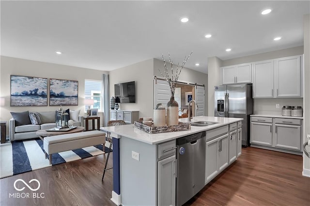 kitchen with stainless steel appliances, a sink, dark wood-style floors, and a barn door