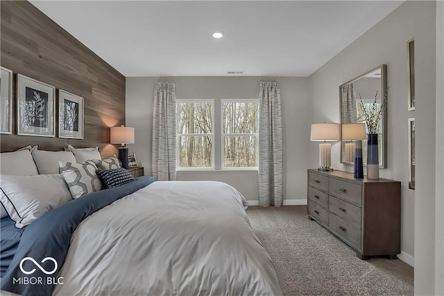 bedroom featuring carpet, visible vents, an accent wall, wooden walls, and baseboards