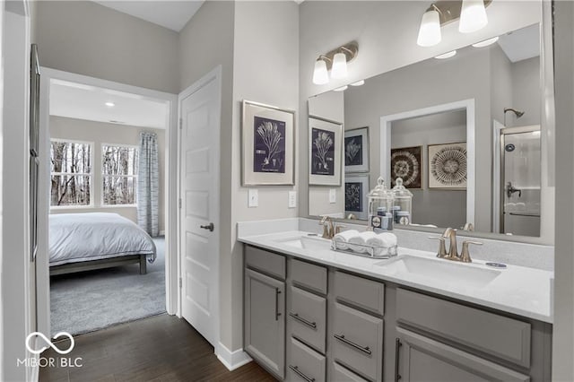 bathroom with double vanity, a shower, a sink, and wood finished floors