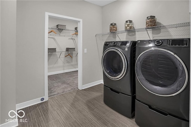 clothes washing area with laundry area, separate washer and dryer, wood finished floors, and baseboards