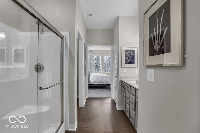 ensuite bathroom featuring vanity, wood finished floors, a shower stall, and visible vents