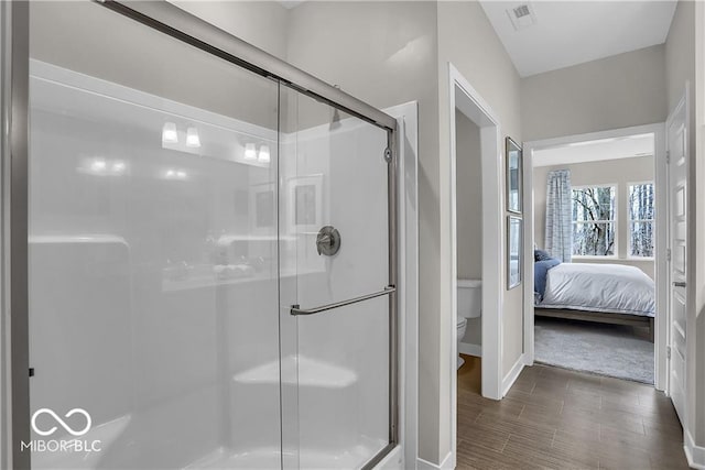 ensuite bathroom with visible vents, a stall shower, connected bathroom, and toilet