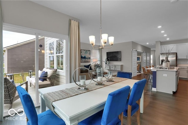 dining space with a notable chandelier, a barn door, dark wood-type flooring, and recessed lighting