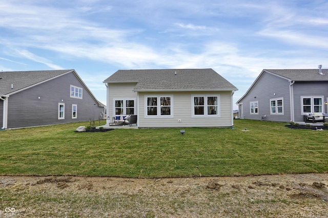 rear view of property featuring a shingled roof, a patio, and a lawn