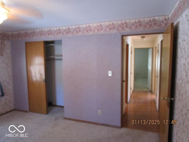 unfurnished bedroom featuring a closet, light colored carpet, and wallpapered walls