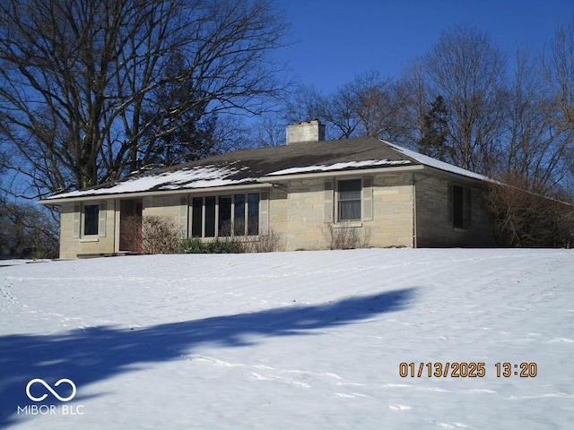 view of snow covered exterior with a chimney