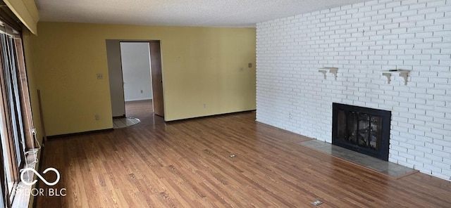 unfurnished living room featuring a textured ceiling, a fireplace, wood finished floors, and baseboards