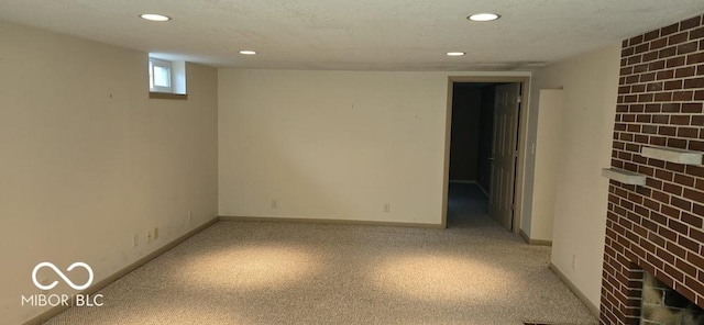 basement featuring a textured ceiling, recessed lighting, a fireplace, and baseboards