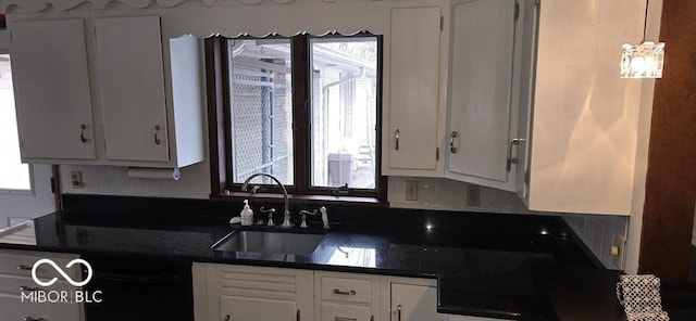 kitchen with plenty of natural light, dark countertops, white cabinets, and a sink