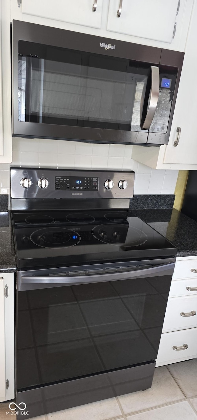 kitchen with white cabinetry, electric range, stainless steel microwave, and dark stone counters