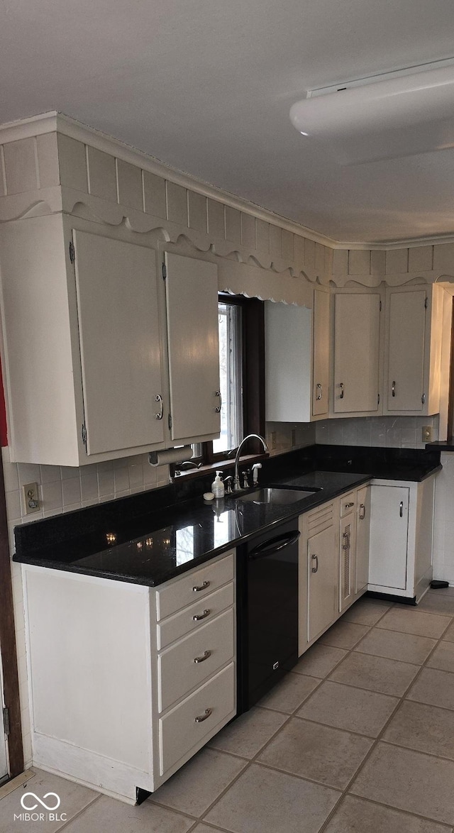 kitchen with black dishwasher, dark countertops, backsplash, white cabinets, and a sink