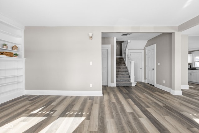 unfurnished living room with dark hardwood / wood-style flooring and built in shelves