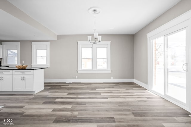 unfurnished dining area featuring a notable chandelier and light hardwood / wood-style flooring