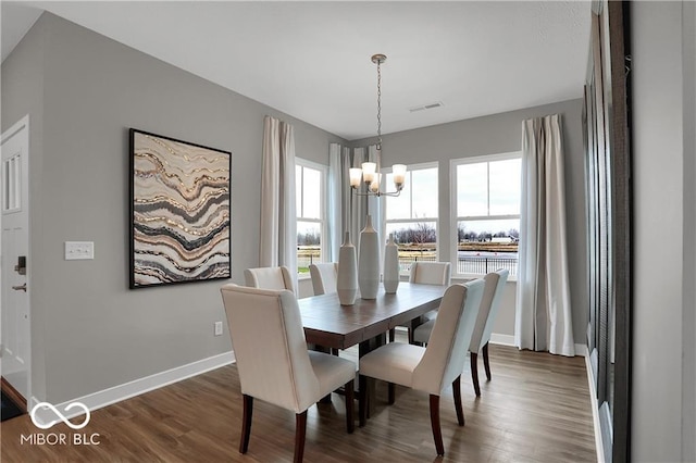 dining area with dark wood-style floors, visible vents, baseboards, and an inviting chandelier