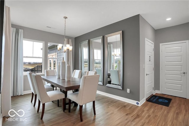 dining space with a chandelier, baseboards, wood finished floors, and a healthy amount of sunlight