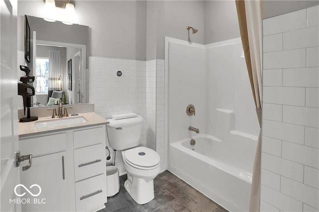 bathroom featuring toilet, bathtub / shower combination, vanity, and tile walls