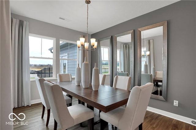 dining room with dark wood-style floors, a chandelier, visible vents, and baseboards