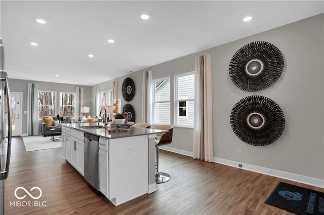 kitchen with a kitchen island with sink, dark wood-style flooring, a sink, open floor plan, and dishwasher