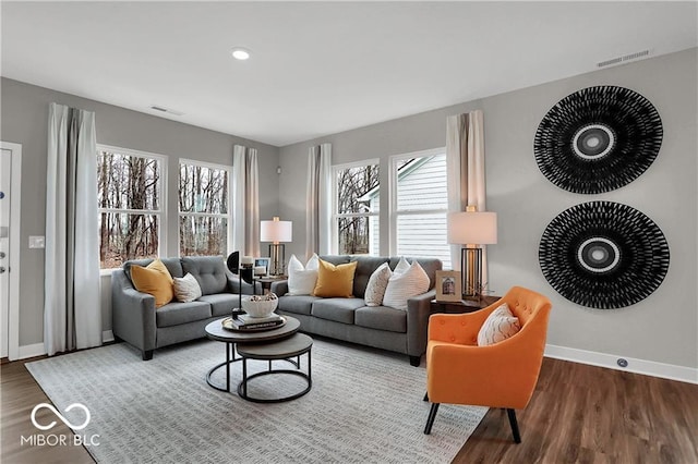 living area with wood finished floors, visible vents, and baseboards