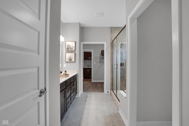 full bathroom with a stall shower, tile patterned flooring, a spacious closet, and vanity