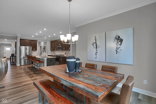 dining area with baseboards, a chandelier, wood finished floors, and ornamental molding