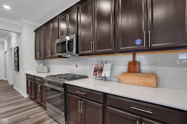 kitchen with dark brown cabinetry, light countertops, ornamental molding, appliances with stainless steel finishes, and decorative backsplash