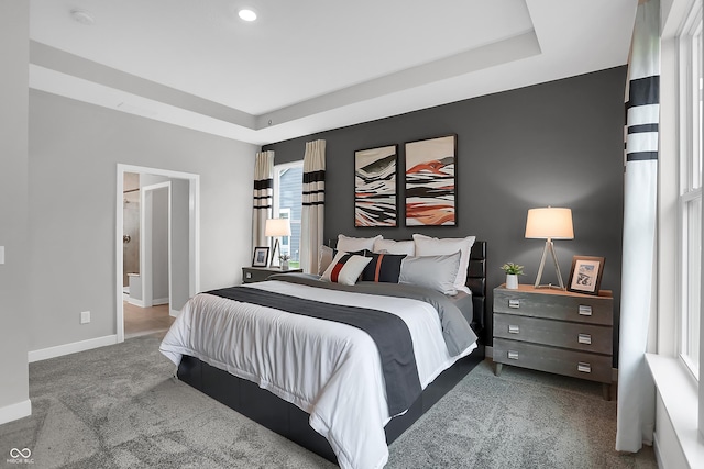 carpeted bedroom featuring baseboards and a tray ceiling