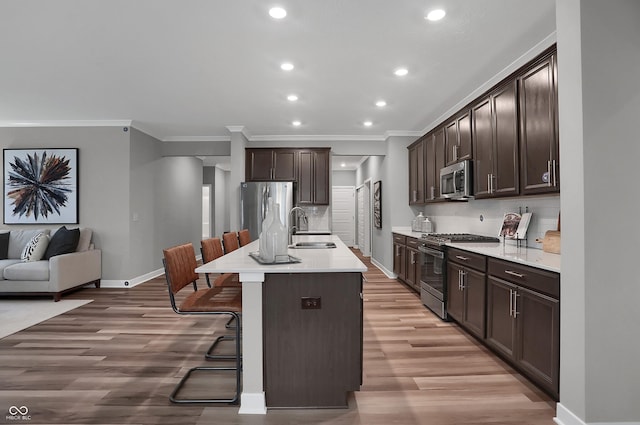 kitchen with appliances with stainless steel finishes, a sink, dark brown cabinetry, and tasteful backsplash